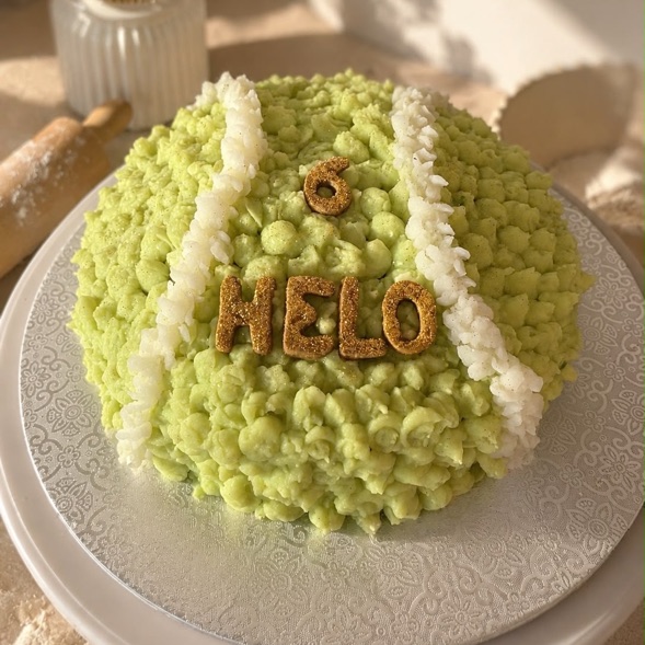 A large custom birthday cake made to look like a tennis ball, with the dog's name and age